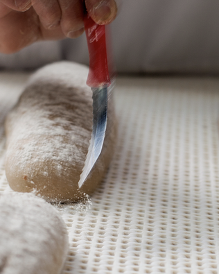Bäcker ritzt einen Teigling — ehrliches Handwerk seit 1647